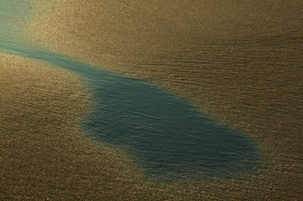 Ciemna smuga wody na złocistym piasku o wschodzie słońca | fot. Marcin Skrobisz