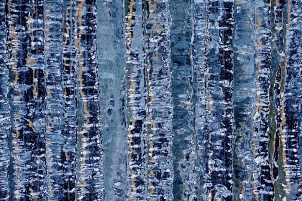Abstrakcyjna struktura lodu z pionowymi smugami i subtelnymi refleksami światła | fot. Marcin Skrobisz