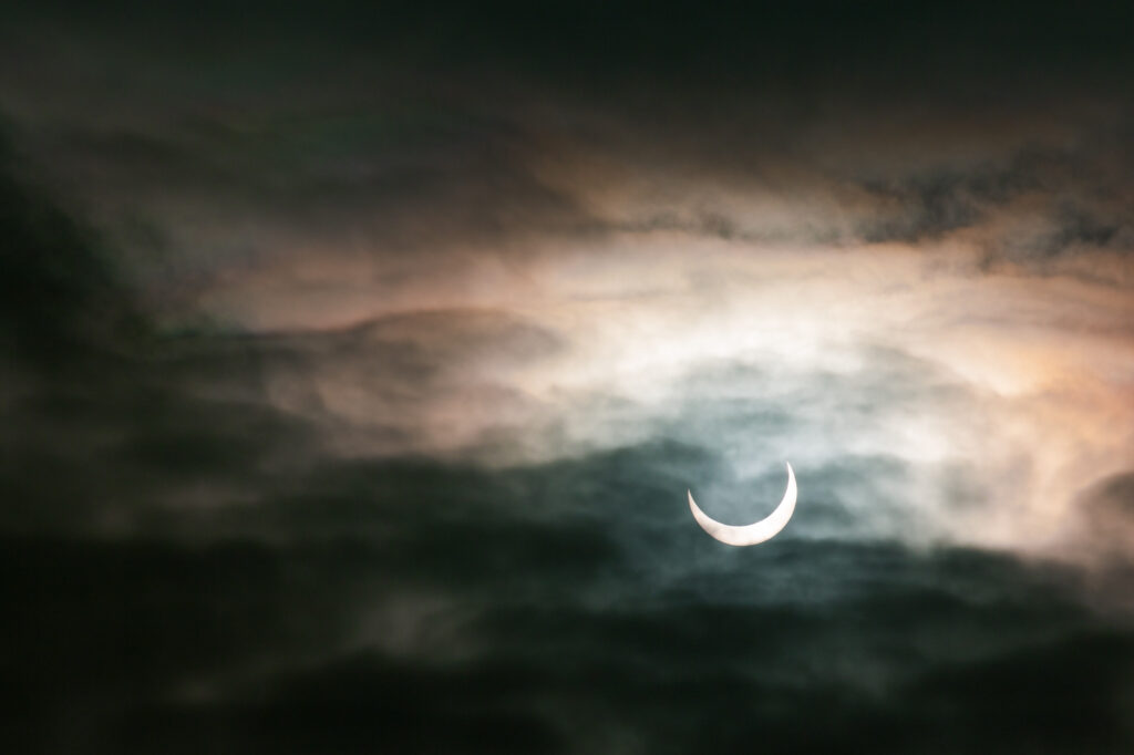 Częściowe zaćmienie Słońca widoczne przez chmury na niebie | fot. Marcin Skrobisz