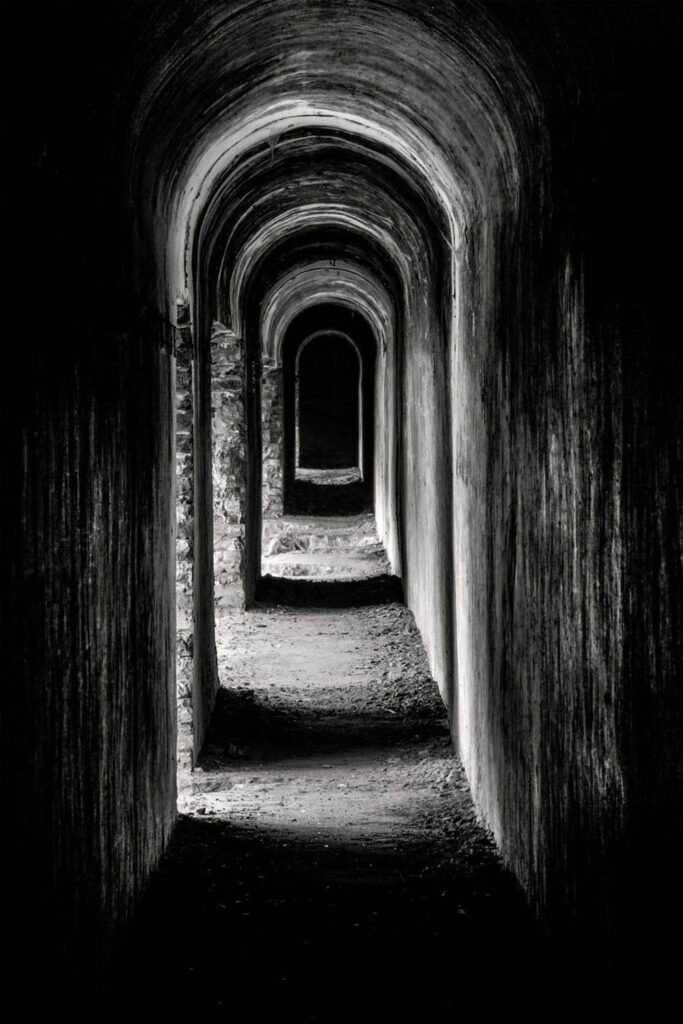 Czarno-białe zdjęcie długiego tunelu fortecznego z wyraźną perspektywą i światłocieniem | fot. Marcin Skrobisz