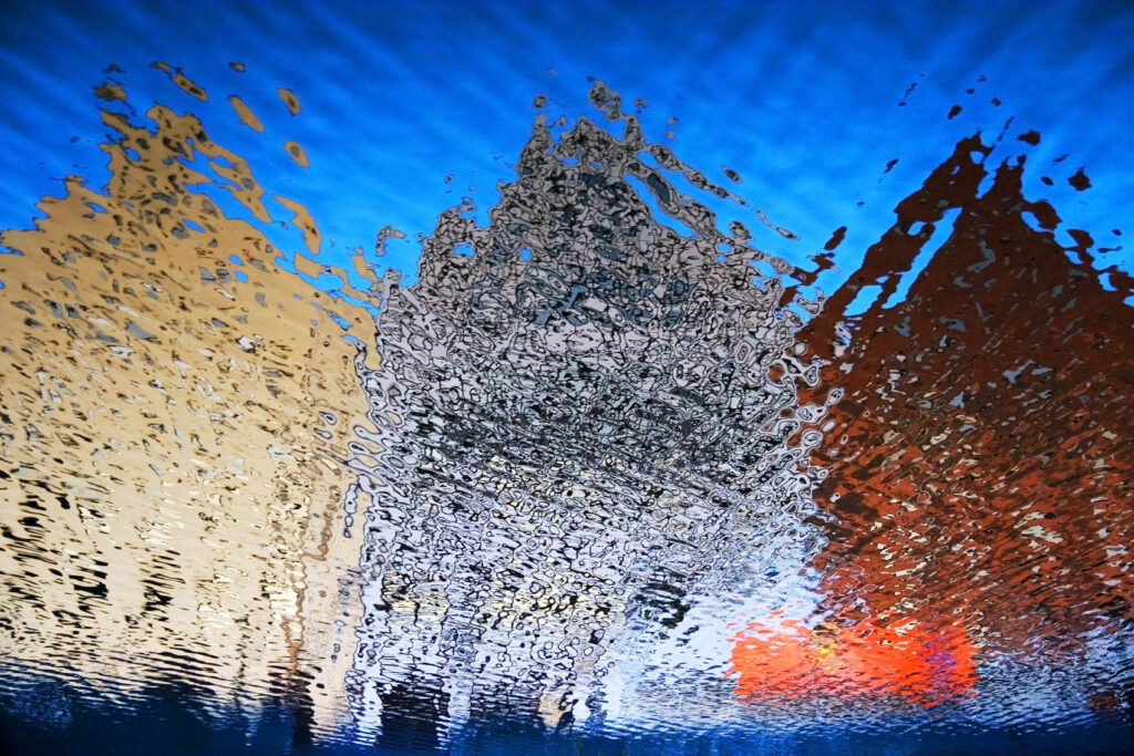 Odbicie kolorowych kamienic w wodzie, tworzące abstrakcyjny, falujący wzór | fot. Marcin Skrobisz