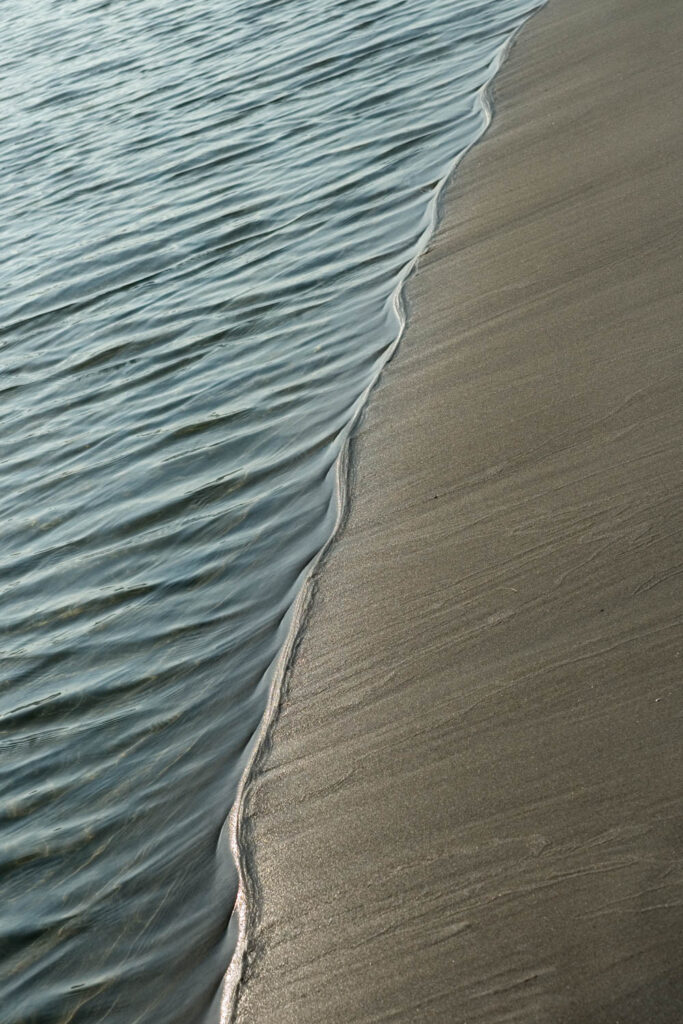 Delikatna fala opływająca linię brzegową piasku – minimalistyczna fotografia przyrody | fot. Marcin Skrobisz